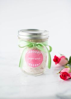 a jar filled with vanilla sugar next to pink roses on a white surface and text overlay reads diy valentine's vanilla sugar scrub