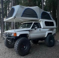 a white truck with a camper on the back parked in front of some trees