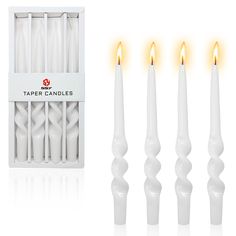 four white candles are lit in front of a box