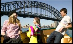 three people on a boat in front of the sydney harbour bridge and opera house, australia