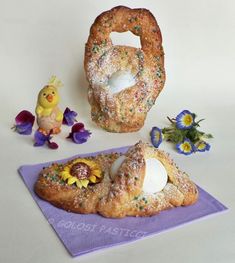 two pastries on a purple napkin next to flowers and an easter egg in the shape of a bagel