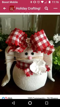 a white stuffed animal with a red and white checkered bow on it's head