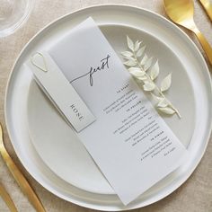 a table setting with place cards and gold cutlery on the plate, along with utensils