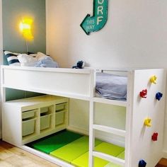 a white bunk bed sitting next to a green rug on top of a hard wood floor