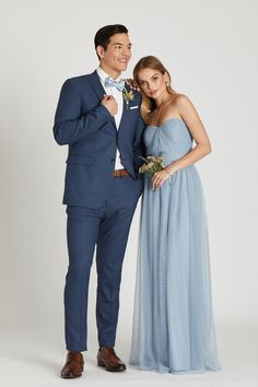 a man in a blue suit standing next to a woman wearing a light blue dress