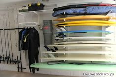 surfboards are stacked on top of each other in a room with white walls and black railings