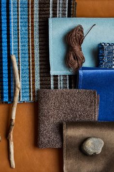 there are many different colors of fabric on the table with some rocks and sticks next to it