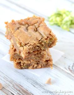 two pieces of brownies sitting on top of each other next to some green leaves