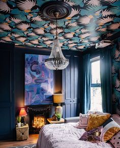 a bedroom decorated in blue and pink with a chandelier hanging from the ceiling