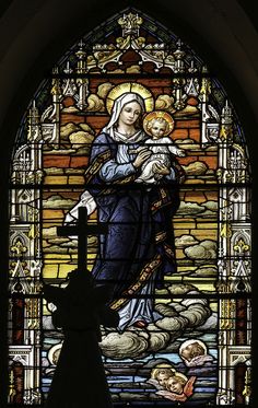 a stained glass window with the image of mary and jesus holding a child in her arms