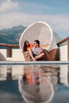 a man and woman sitting in a chair next to a pool