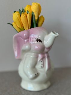 an elephant vase with yellow flowers in it