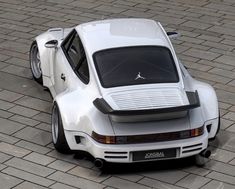 a white sports car parked on top of a brick road