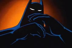 the batman logo is lit up in blue and black colors on a dark background with an orange light behind it