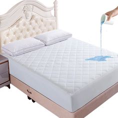 a person is pouring blue liquid on a bed with a white headboard and foot board