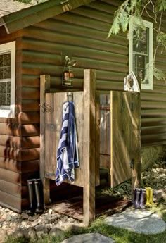 the outside of a wooden cabin with towels hanging from it's hooks and towel rack