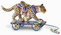 an animal figurine is riding on a toy cart with wheels and colorful decorations