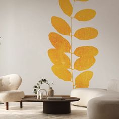 a living room with white furniture and yellow leaves on the wall