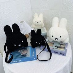 three stuffed animals sitting on top of a white table next to a book and lamp