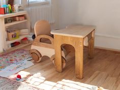 a child's wooden table and chair in a room with toys on the floor