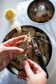 two hands are holding shrimp in a pot