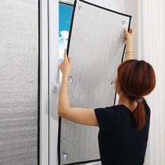 a woman writing on a screen in front of a window with an electronic device attached to it