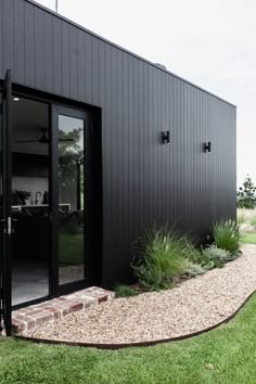 a black building with glass doors and gravel path leading up to the front door area