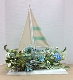 a small sailboat with succulents and greenery