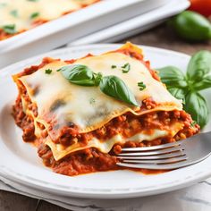 a white plate topped with lasagna covered in sauce and cheese next to a fork