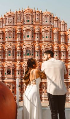 a man standing next to a woman in front of a building