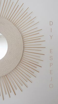 a white circular mirror with wooden sticks in the shape of sunbursts and words diy espejo