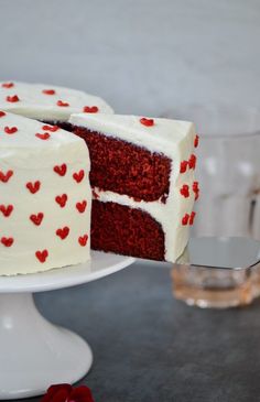 a red velvet cake with white frosting and hearts on the outside, cut in half