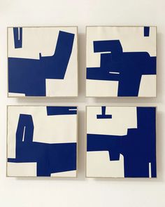 four blue and white abstract paintings mounted to a wall