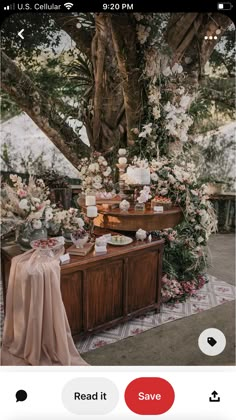 a table with flowers and candles under a tree