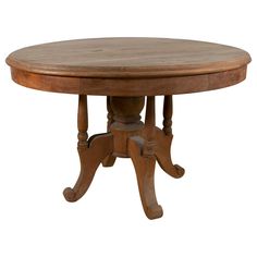 a round wooden table with two leaves on the top and one leaf at the base