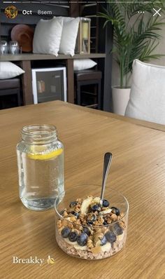 a glass bowl filled with granola and blueberries on top of a wooden table