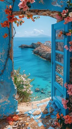 an open blue door with flowers growing out of it and the ocean in the background