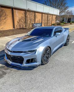 a silver chevrolet camaro parked in front of a building