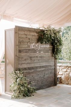 a wooden wall with the words the grooms on it and greenery in front