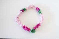 a bracelet with pink, green and white beads is displayed against a white background in this image