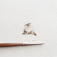 an animal is sitting on top of a piece of paper next to a paintbrush