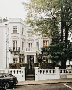 a black car parked in front of a white building with balconies on the windows