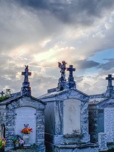 an old cemetery with crosses and flowers on the headstones under a cloudy blue sky