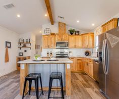 a kitchen with an island and two stools in front of the sink, refrigerator and stove