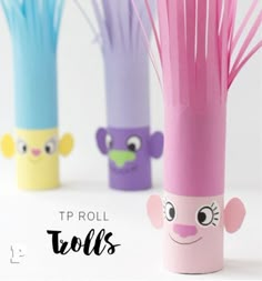 three toilet paper rolls with faces and hair on them, one is pink, the other is blue