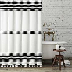 a bath tub sitting next to a shower curtain in a bathroom with white brick walls