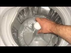 a hand is holding an object in the middle of a washing machine