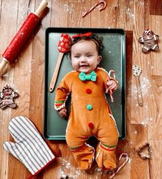 a baby laying on top of a tray next to christmas decorations