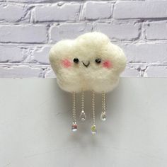 a white cloud with pink eyes and chains hanging from it's side against a brick wall