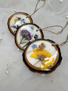 three wooden ornaments with dried flowers on them